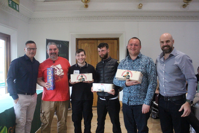 Group of employees holding gift boxes and prizes indoors during a team presentation event.