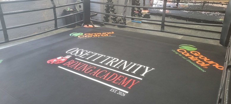 Branded training ring mat displaying “Ossett Trinity Boxing Academy” with sponsor logos around the edges.